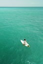 Vertical aerial view of a sexy female surfer sitting on a surfboard on a line-up Royalty Free Stock Photo