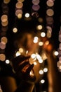 Mesmerizing Bokeh Effect with Glowing Festive Fairy Lights and Hands Creating a Creative Silhouette Against Dark Background Royalty Free Stock Photo