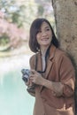 Vertical Asian Women with vintage film camera take a photo. Smiling female photographer look at photo from professional camera Royalty Free Stock Photo