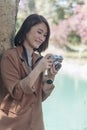 Vertical Asian Women with vintage film camera take a photo. Smiling female photographer look at photo from professional camera Royalty Free Stock Photo