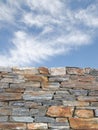 Vertical background with rough stone wall and blue cloudy sky Royalty Free Stock Photo