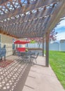 Vertical Backyard patio with attached wooden pergola roof and covered barbecue griller