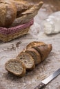 Baguette bread cut in slices with basket of various bread forms on wooden table Royalty Free Stock Photo