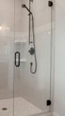 Vertical Bathroom shower stall with half glass enclosure adjacent to built in bathtub Royalty Free Stock Photo