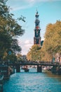 Vertical of a beautiful Amsterdam view, the historic Westertorenlandmark captured behind a bridge