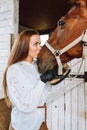 Vertical beautiful cowgirl horse woman equestrienne kissing in breeches, shirt, belt. Cleaning brushing grooming mane Royalty Free Stock Photo