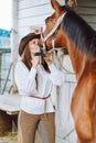 Vertical beautiful horse woman cowgirl equestrienne kissing companion. Breeches, shirt. Cleaning brushing grooming mane Royalty Free Stock Photo