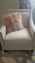 Vertical Bedroom interior with faux fur throw pillow on a white upholstered armchair
