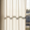 Vertical beige curtains gently filter sunlight through a window, creating a shadow with a wavy Royalty Free Stock Photo