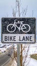 Vertical Bike Lane sign post in front of a tree and snow covered landscape in winter