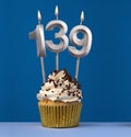 Vertical birthday card with cupcake - Lit candle number 139 on blue background Royalty Free Stock Photo