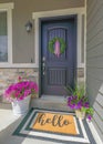 Vertical Black front door of a house with wreath and potted flowers at the front Royalty Free Stock Photo