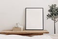 Vertical black picture frame mockup on vintage bench, table. Cup of coffee on pile of books. Potted olive tree. White Royalty Free Stock Photo
