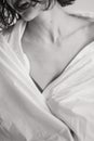 Vertical black and white frame of a girl in a blanket. Close up of female clavicle