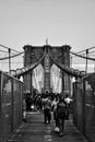 Vertical black and white shot of the Brooklyn Bridge with a walking crowd