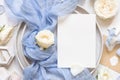 Card near blue tulle fabric knot and cream roses on plates top view copy space, wedding mockup