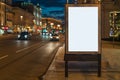 Vertical blank glowing billboard on night city street. In background buildings and road with cars. Mock up. Royalty Free Stock Photo