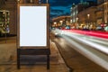 Vertical blank glowing billboard on night city street. In background buildings and road with cars. Mock up. Royalty Free Stock Photo