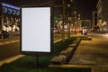 Vertical blank glowing billboard on night city street. In background buildings and road with cars. Mock up. Royalty Free Stock Photo