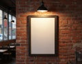 Vertical blank poster with dark frame on rustic red brick wall. Warm overhead light illuminates empty space for text or artwork. Royalty Free Stock Photo