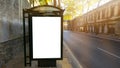 Vertical blank white billboard at bus stop on city old street. In the background buildings and road