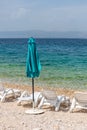 Vertical of an blue beach umbrella and lounge chairs in a  relaxing environment by the sea Royalty Free Stock Photo