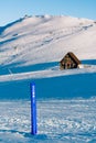 Vertical of a blue summit pole in a majestic ski resort with a wooden small house in the background