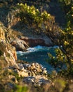 Vertical of blue waves crashing the cliffs on a sunny shore of the Mani Peninsula, Greece Royalty Free Stock Photo