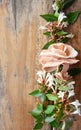 Vertical bouquet of white flowers mixed with a fabric pink rose on rustic woos background.Copy space