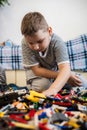 Vertical. A boy sitting on the floor in a children's room collects parts from a construction set. The child is Royalty Free Stock Photo