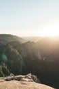 Vertical breathtaking scenery of the sun rising over a rock formation covered in greenery