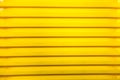 Vertical bright stripes of plastic basins stacked in a pile of yellow. Abstraction, structures,