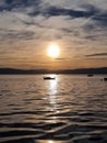 Vertical of a bright sunlight captured over a sea with small boats at sunset Royalty Free Stock Photo