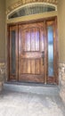 Vertical Brown wooden front door of home with sidelights and arched transom window