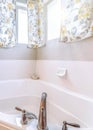 Vertical Built in bathtub with stainless steel faucet inside bathroom with floral curtain