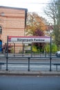 Vertical of a bus stop Burgerpark Pankow outdoors, with a sign on it, trees, buildings background