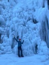 VERTICAL: Cheerful Caucasian woman ice climbing outstretches her arms in joy. Royalty Free Stock Photo