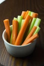 Vertical close up filled frame isolated shot of party snack food. A white bowl of crunchy orange carrot and juicy green celery Royalty Free Stock Photo