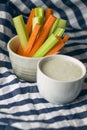 Vertical close up filled frame shot of party snack food. A bowl of crunchy orange carrot and juicy green celery sticks with a