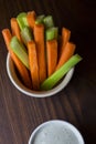 Vertical close up isolated top view shot of a bowl of party snack in form of orange carrot and green celery sticks with a white Royalty Free Stock Photo