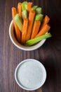 Vertical close up isolated top view shot of a bowl of party snack in form of orange carrot and green cerely sticks with a white Royalty Free Stock Photo