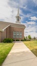 Vertical Close up of pathway leading to a church with white steeple under cloudy blue sky Royalty Free Stock Photo