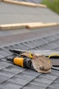 Asphalt tile roof and tool belt lying on new house under construction Royalty Free Stock Photo