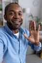 Vertical close-up photo of a young African-American man talking to the camera on a video call, recording, waving and Royalty Free Stock Photo