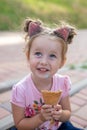 Vertical close-up portrait of a cute baby girl with ice cream on a walk