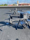 Vertical close-up shot of two drones on asphalt with building in the background