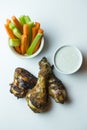 Vertical close up top view shot of isolated grilled barbecue chicken wings, legs, a bowl of fresh orange carrots and juicy green Royalty Free Stock Photo