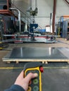 vertical close-up of an unrecognizable worker using a remote control to use the suction cup machine to transport large metal