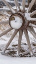 Vertical Close up of the wooden wheel of an old wagon against a snowy terrain in winter Royalty Free Stock Photo