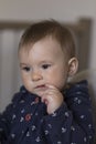 Vertical closeup of adorable fair toddler girl sitting in high chair sucking on a piece of cucumber